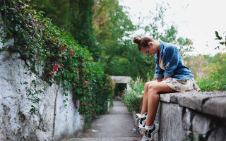 Young girl sitting cherry blossoms - a stone wall free wallpaper