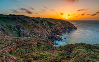 Sunset cliff lake grassy cloudy - a sunset over a rocky cliff free wallpaper