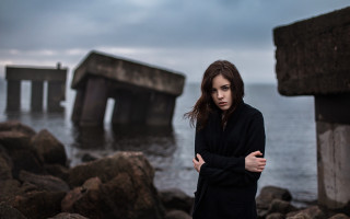 Woman rocks ocean crossed arms - a dark sky in the background free wallpaper