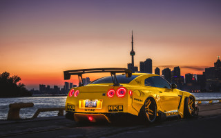 Yellow sports car road water 2 - a city skyline in the background free wallpaper