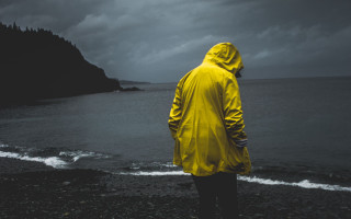 Man yellow raincoat beach ocean - daniel lieske free wallpaper