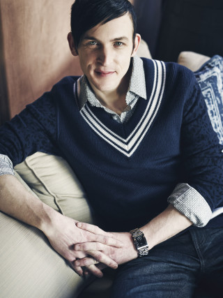 Man sitting couch sweater smile - free dark wallpaper