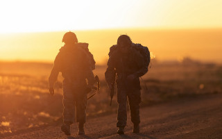Soldiers dirt road sunset backlit - the sun setting behind them free wallpaper