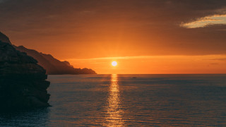 Sunset ocean boat mountain city - the water and a mountain in the distance free wallpaper