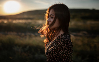Woman sunset field blowinghair profile - the sun setting behind her free wallpaper