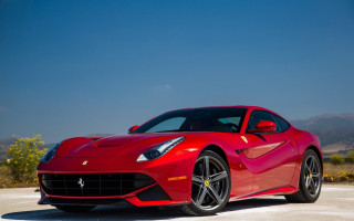 Red ferrari mountains blue sky - a parking lot free wallpaper