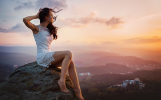 Woman sitting rock wind sunset - top of a rock free wallpaper