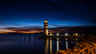 Lighthouse night water bridge city - a pier in the background free wallpaper