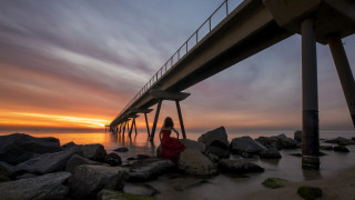 Woman rocks bridge sunset ocean - under a bridge free wallpaper