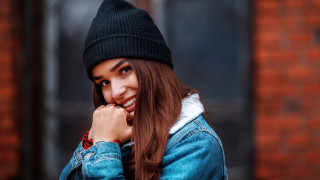 Woman denim jacket beanie smiles - a brick building free wallpaper