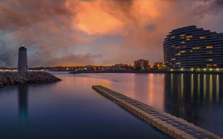 Lighthouse night cloudy sky water - a dock in the foreground free wallpaper