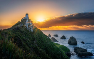 Lighthouse hill sunset ocean rocks - the sun setting behind free wallpaper