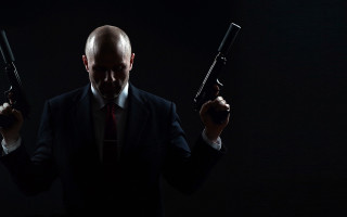 Man in suit holding guns - cinematic photography free wallpaper