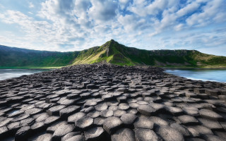 Large rock formation mountain water - a mountain in the background and a body of water free wallpaper