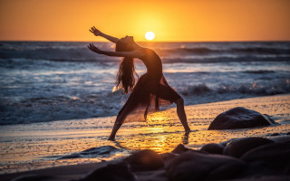 Woman beach sunset outstretched arms - behind her free wallpaper