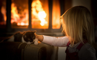 Little girl petting cat fireplace - warm free wallpaper