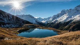 Mountain lake sunburst grassy field - a grassy field in the foreground free wallpaper