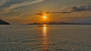Sunset mountain boat water cityscape - a mountain in the background and a boat free wallpaper