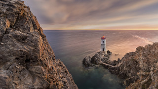 Lighthouse rocky cliff ocean sunset 3 - the water below free wallpaper