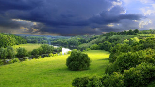 Green field river cloudy sky - stormy weather free wallpaper