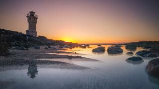 Lighthouse rocky shore sunset ocean 3 - a lighthouse free wallpaper