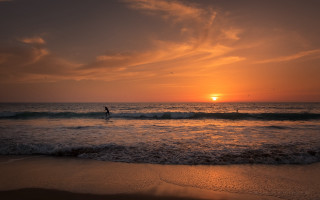 Surfing sunset ocean cityscape mountains - a surfboard in the ocean free wallpaper
