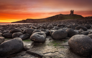 Rocky beach castle sunset mountains - a red sky in the background free wallpaper