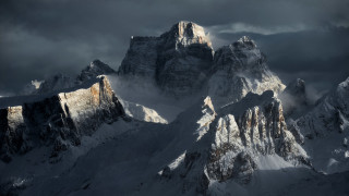 Mountain range snow capped cloudy - a dark sky in the background free wallpaper
