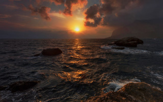 Sunset ocean rocky shore cityscape - a sunset over the ocean free wallpaper for desktop