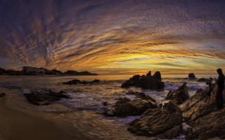 Ocean sunset rock person colorful - a building in the distance free wallpaper