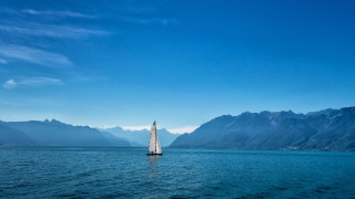 Sailboat mountains blue sky clouds - a sailboat free wallpaper