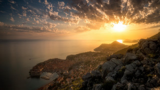 Sunset rocky cliff water town - a sunset over a rocky cliff free wallpaper