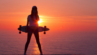 Woman surfboard pier sunset ocean - the sun setting behind her free wallpaper