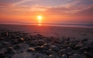 Sunset beach rocks water person - a sunset over a beach free wallpaper