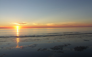 Sunset ocean beach surfboard mountain - a surfboard in the foreground free wallpaper