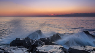 Rocky shore waves sunset pink - against the rock free wallpaper
