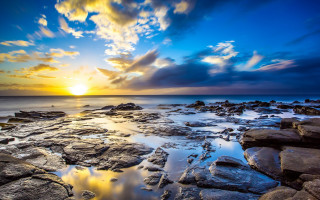Sunset rocky beach water clouds 7 - a sunset over a rocky beach free wallpaper