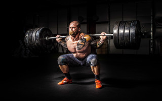 Muscular man squatting barbell dark - a barbell free wallpaper