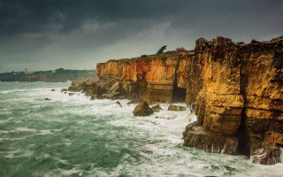 Rocky cliff lighthouse stormy water - a dark sky above free wallpaper