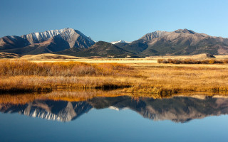 Mountain range lake grassy field - a grassy field in the foreground free wallpaper
