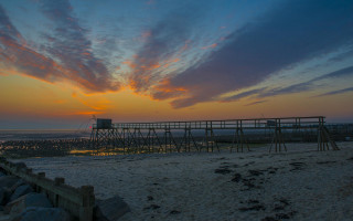 Sunset beach wooden structure cityscape - a sunset over a beach free wallpaper