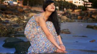 Woman beach rock sky building - a building in the background free wallpaper