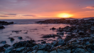 Sunset rocky beach water cityscape 2 - a sunset over a rocky beach free wallpaper