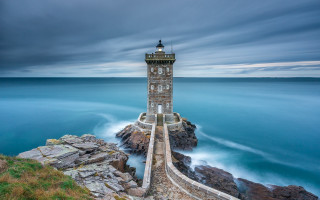 Lighthouse rocky cliff ocean cloudy 3 - the ocean under a cloudy sky free wallpaper