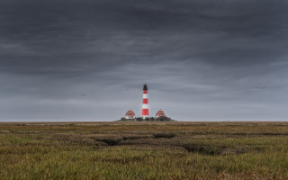 Lighthouse grassy island cloudy sky - overhead in the distance free wallpaper