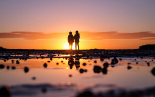 Beach sunset couple silhouette bokeh - the sun setting behind them free wallpaper for desktop