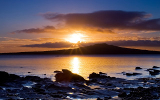 Sunset water rocks mountain city - the foreground and a mountain in the background free wallpaper