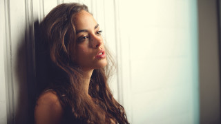 Woman leaning wall serious portrait 5 - the side with free wallpaper