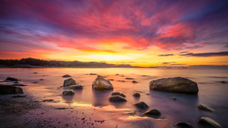 Sunset beach rocks clouds mountain - a sunset over a beach free wallpaper