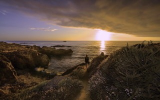 Cliff overlooking ocean sunset cloudy - a cloudy sky above them free wallpaper